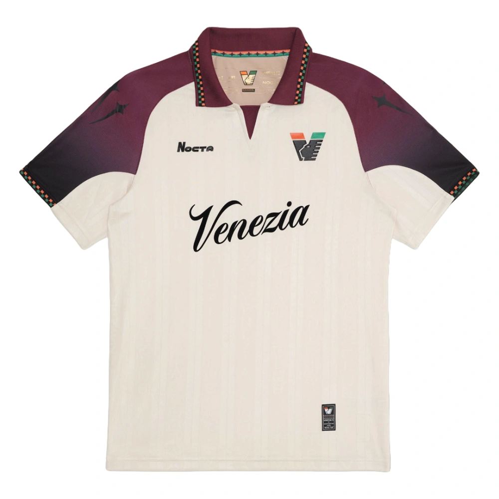 NOCTA Venezia Away Kit 25/26 in cream with burgundy and black details, retro football collar, short sleeves, front view.
