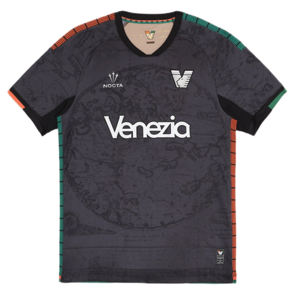 NOCTA Venezia Home Kit 25/26 in black with bold orange and green details, V-neck, short sleeves, front view.