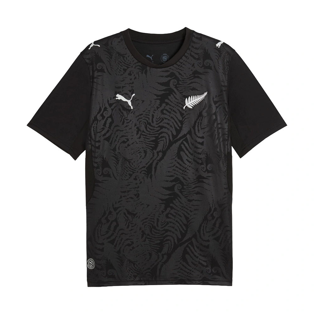 Front view New Zealand Home Kit 2026 by PUMA. Black base, silver fern pattern, short sleeves.
