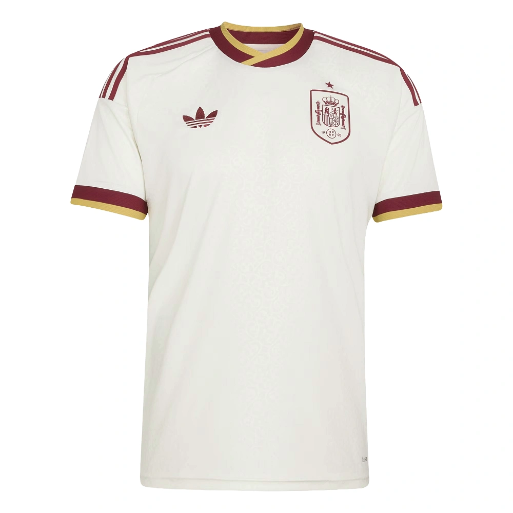 Adidas Spain Away Kit 2026, front view, off-white with manuscript pattern, gold and burgundy cuffs, short sleeves.